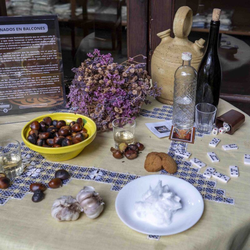 Mesa en honor a los finados. Una mesa puesta con comida, vino, flores y juegos.