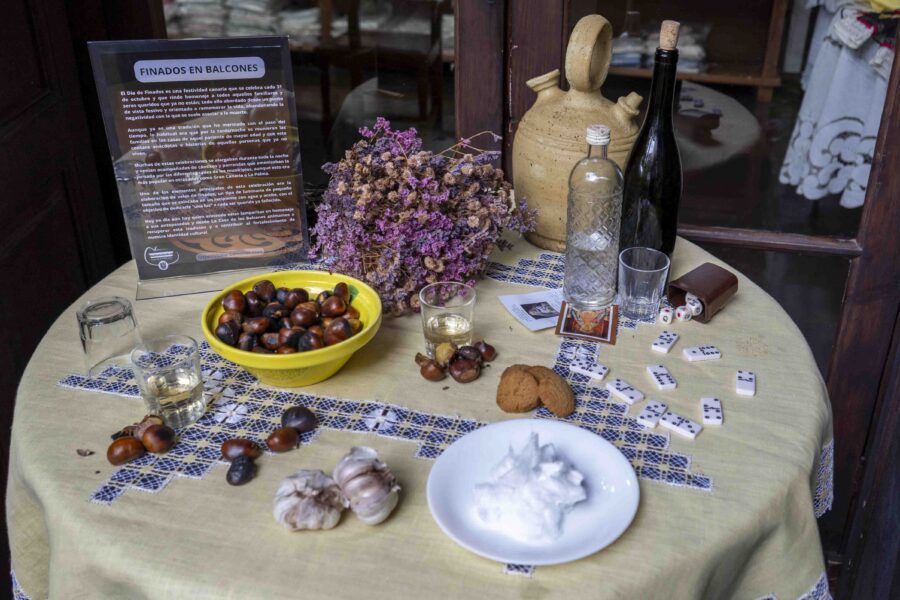 Mesa en honor a los finados. Una mesa puesta con comida, vino, flores y juegos.